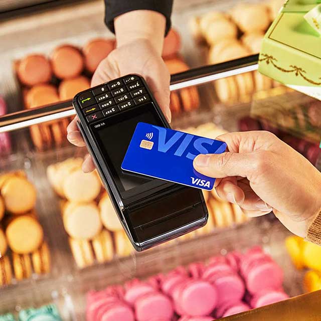 An individual using a Visa contactless card to buy cookies.