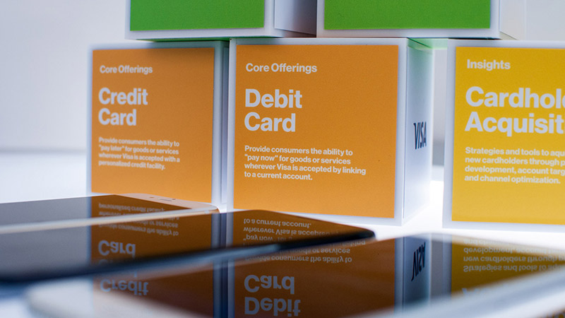 Three colored cubes at the Visa Innovation Center in Miami each with terms written on them, including credit card, debit card, and cardholder acquisition. 