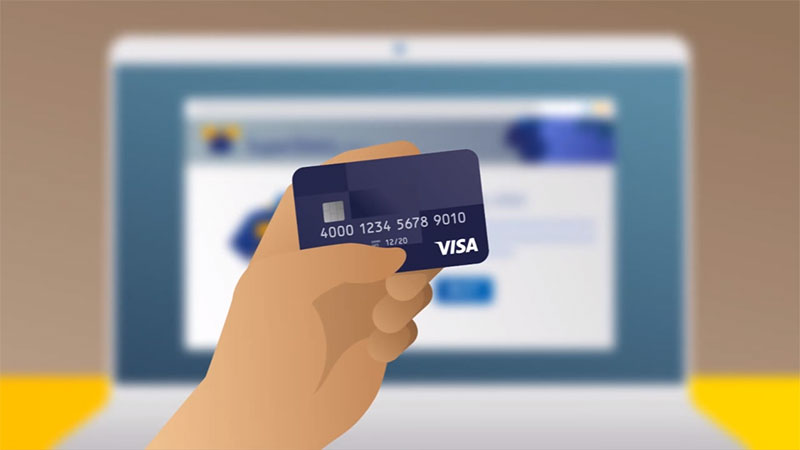 A hand holding a Visa credit card in front of a laptop, highlighting the availability of secure payment options. 