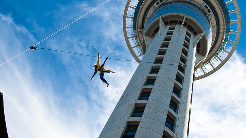 Auckland Sky Tower from below with blue sky and someone jumping off.