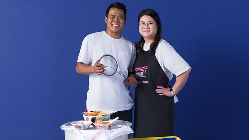 A man and a woman posing in front of a table with food, depicting the importance of shopping local.