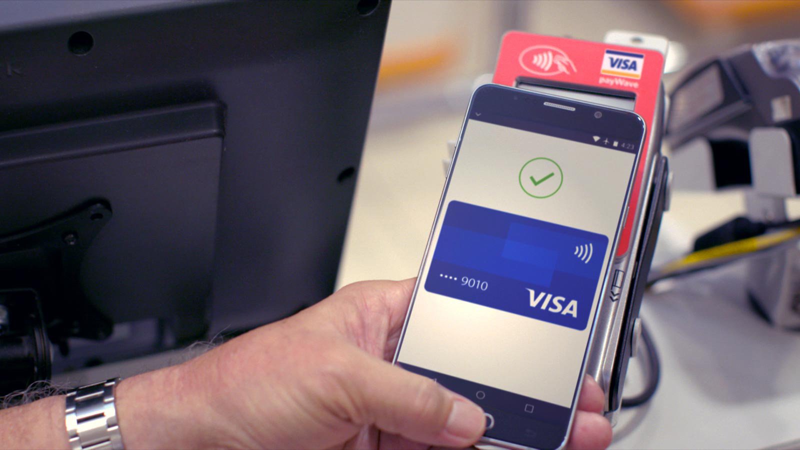 A Visa card displayed on a smartphone held by a person, utilizing mobile contactless payments for fast and secure transactions. 