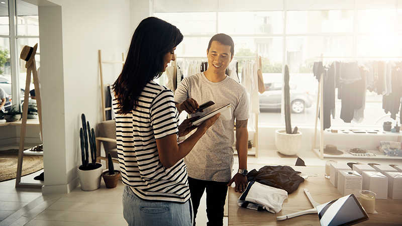 : A man and woman in front of a clothing store, acknowledged as Google Play Merchant. 